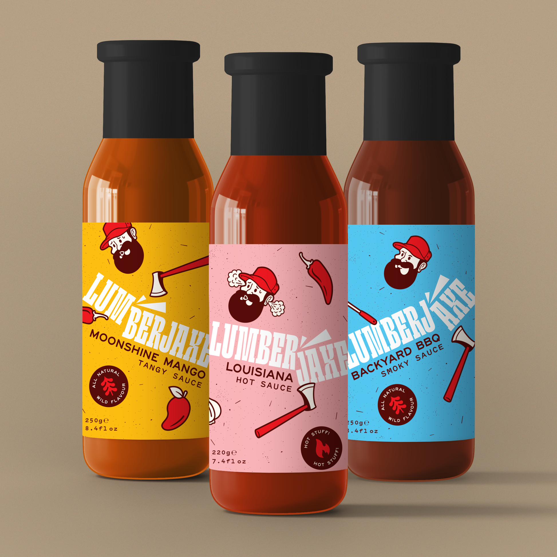 Three bottles of hot sauce from the 'Lumberjaxe' brand displayed against a neutral beige background. Each bottle has a black cap and a colorful label featuring a bearded lumberjack logo with an axe. The leftmost bottle has a yellow label and is named 'Moonshine Mango Tangy Sauce.' The middle bottle has a pink label and is named 'Louisiana Hot Sauce.' The rightmost bottle has a blue label and is named 'Backyard BBQ Smoky Sauce.' The labels also include small illustrations of chili peppers and axes, emphasizi